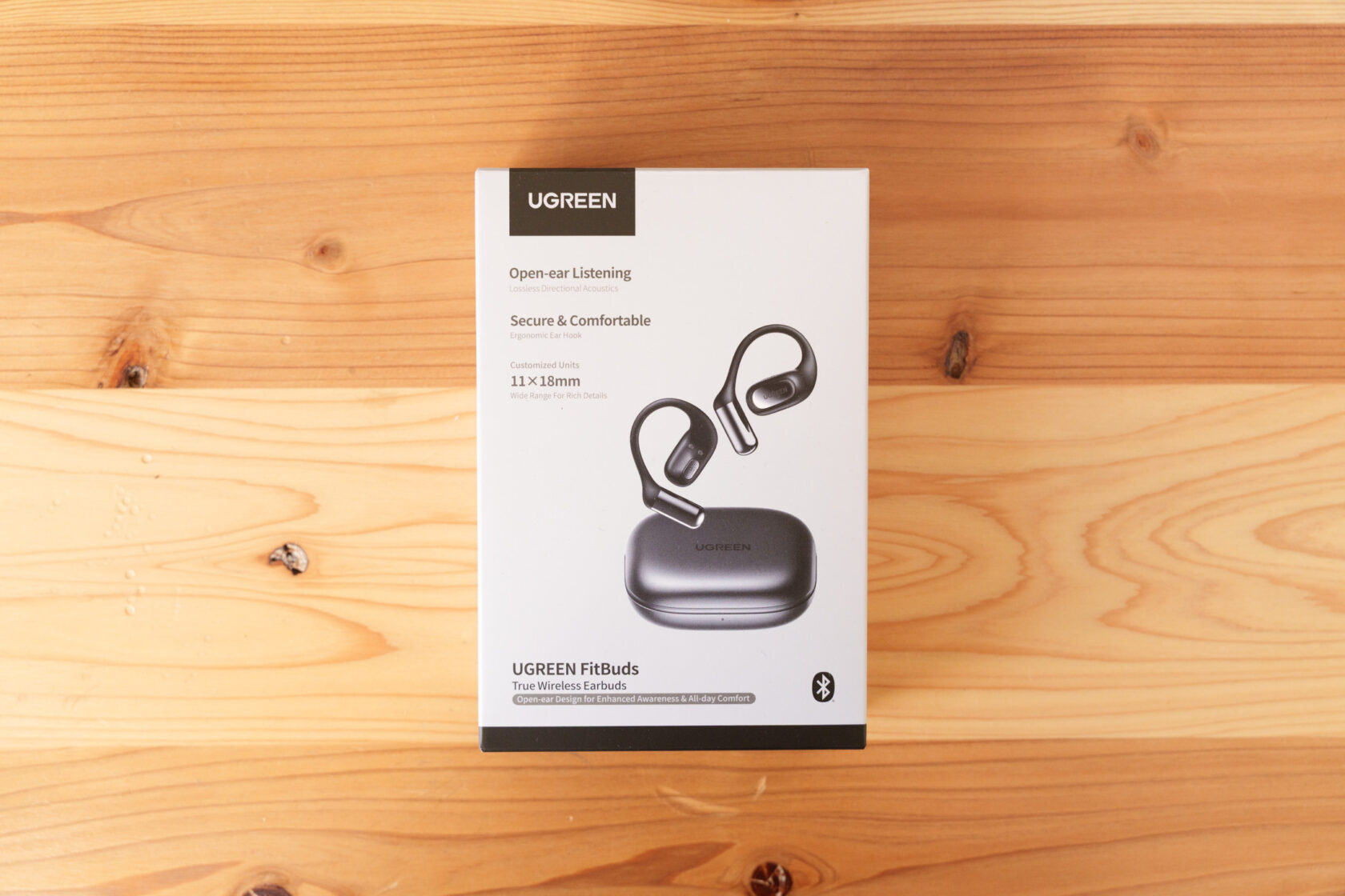 木のテーブルに置かれたUGREENのワイヤレスイヤホン外箱