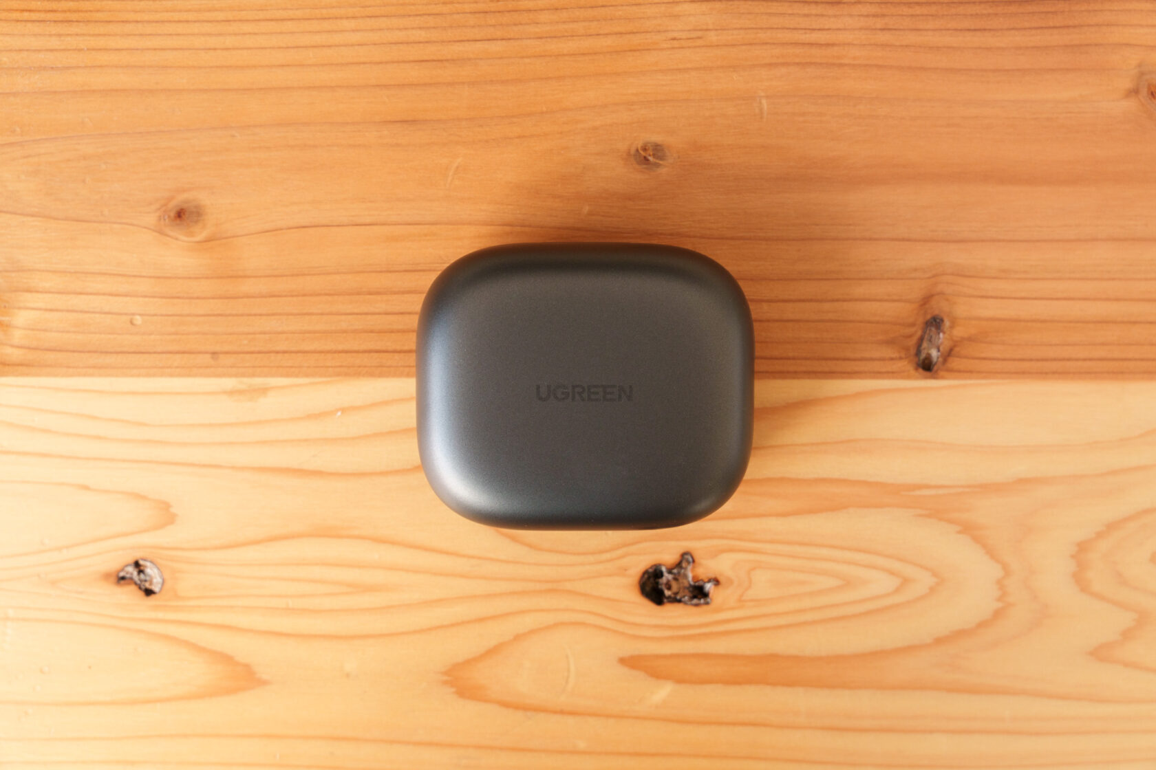 木目の上に置かれたUGREENロゴ入り充電ケース